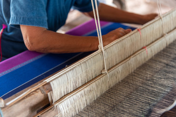 Close-up of hands working a traditional weaving loom